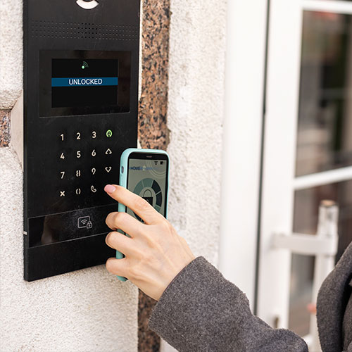 Imagen de placa de acceso con lector NFC donde una persona acercando su móvil.